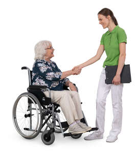 older woman in a wheelchair greeting a physical therapist