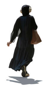 backlit muslim woman with headphones walking