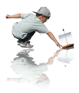 cut out little boy playing with a toy boat by the pond