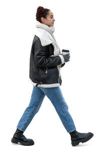 side view of a woman walking with a takeaway coffee in winter