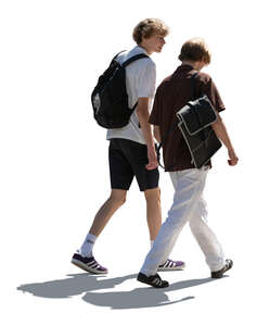 two backlit teenage boys walking