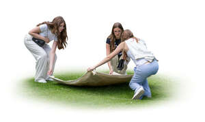 three girls laying a picnic blanket on the grass