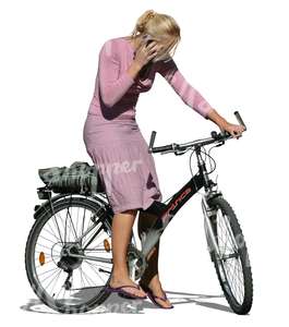 blond woman standing with a bike while on the phone