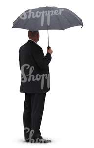man in a black suit standing under an umbrella