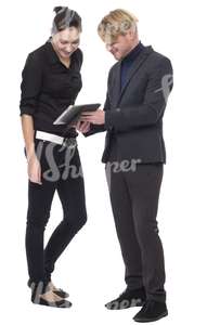 man and a woman standing and looking at the ipad