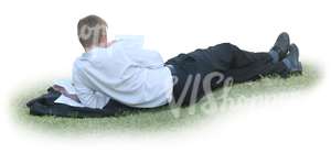 businessman lying on the grass and reading
