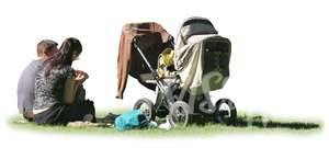 man and woman with a baby carriage sitting on the grass