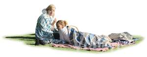 two women wrapped in blankets sitting on the grass