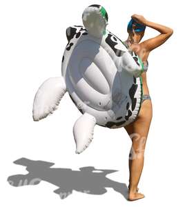 woman in a bikini with an inflatable toy walking on the beach