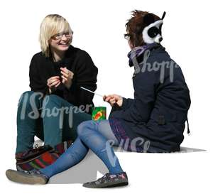 two girls sitting and talking on the sidewalk