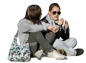 two girls sitting and talking on the sidewalk
