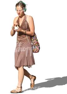 woman with headphones walking and eating icecream