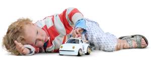 little boy lying and playing with a toy car