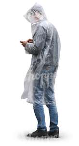 man in a raincoat standing and looking at his smartphone