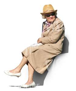 elderly woman in a beige spring coat sitting in the sun