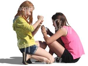 two girls sitting on the ground and playing