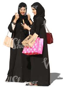 two young arab women in abayas standing and smiling