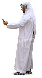 arab man in a white thobe looking at his phone