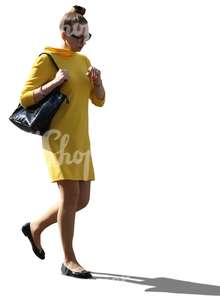 cut out backlit woman in a yellow dress walking