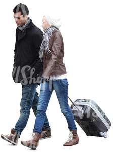 man and woman walking and pulling a suitcase