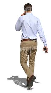 man in a white shirt walking and talking on the phone