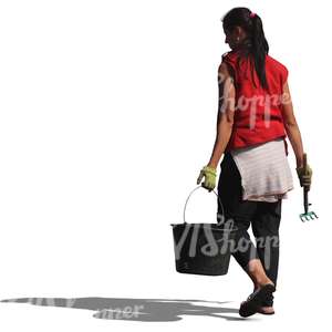 woman with a rake and a bucket walking