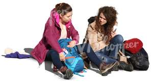 two women sitting on the sidewalk and talking