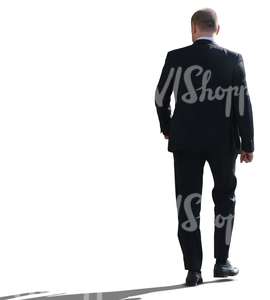 backlit businessman walking seen from behind