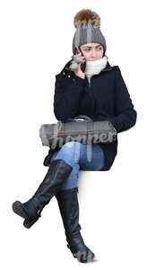 woman in a winter coat sitting and talking on the phone
