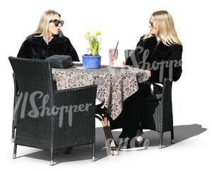 two blonde women sitting in a street cafe and talking