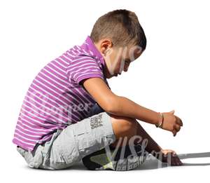 small boy sitting on the ground and playing