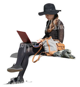 woman with a large hat sitting and working with a laptop.