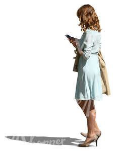 woman wearing a blue dress standing and looking at her phone