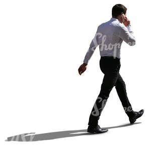 backlit businessman walking and talking on the phone