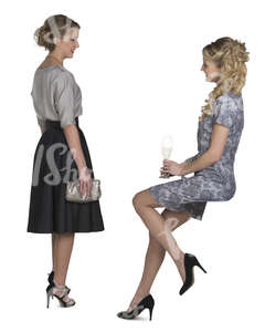 two women in cocktail gowns talking in a bar