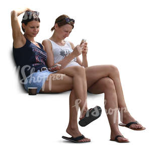 two young women sitting and looking at their phone