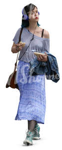 young woman with headphones walking and eating a sandwich 