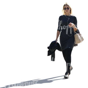 backlit blond woman in black clothes walking and listening to music