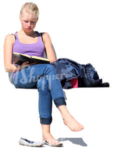 teenage girl sitting outside and reading a book