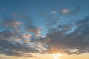 sunset sky with sun visible under the clouds