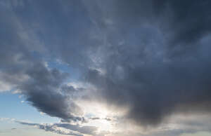 daytime sky with sun under the edge of grey cloud