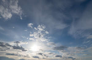 afternoon sky with sun and small clouds