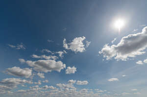 daytime sky with sun and small backlit clouds