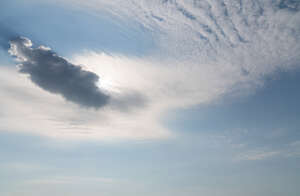 pale blue daytime sky with sun behind a small cloud