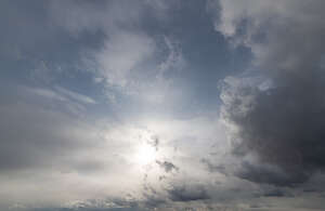 daytime sky with sun shining through a thin cloud