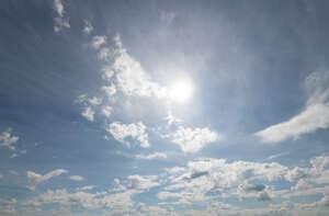 daytime sky with sun and small clouds