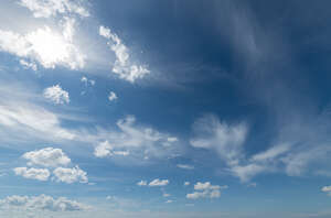 deep blue sky with sun and small clouds