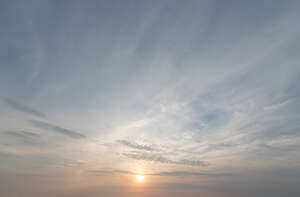 sky with sun setting behind thin clouds