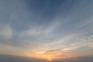 sunset with small sun shining through clouds