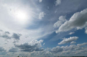 daytime sky with sun and white clouds